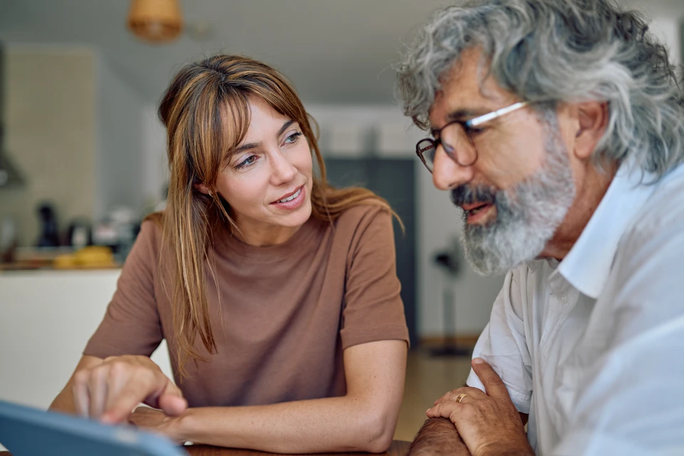 Gros plan professionnel d'une main de conseiller pr&eacute;sentant un document ou un formulaire d'aide financi&egrave;re (MaPrimeR&eacute;nov', CEE ou &eacute;co-PTZ) &agrave; un client en train de le consulter, dans un cadre int&eacute;rieur modern de type bureau ou salon, avec &eacute;ventuellement des plans ou devis de r&eacute;novation &eacute;nerg&eacute;tique visibles en arri&egrave;re-plan. La sc&egrave;ne doit transmettre la confiance et la clart&eacute; administrative d'une d&eacute;marche de subvention accompagn&eacute;e par un professionnel expert.