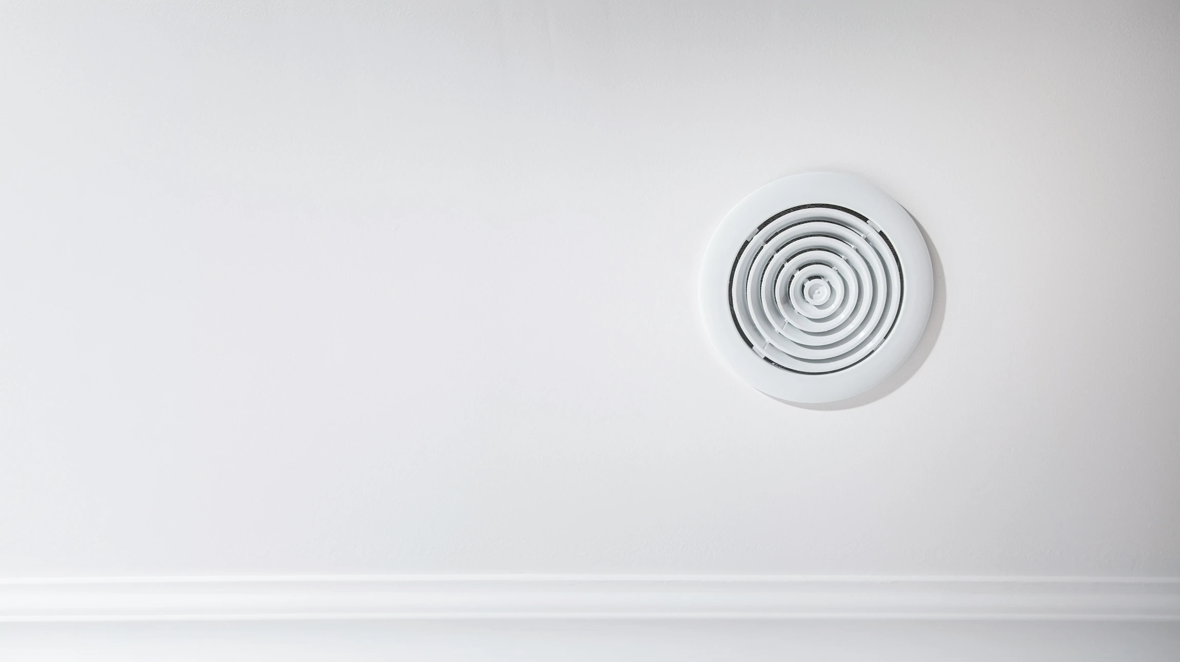 Un technicien en tenue de travail bleue installe des conduits de ventilation dans un local technique